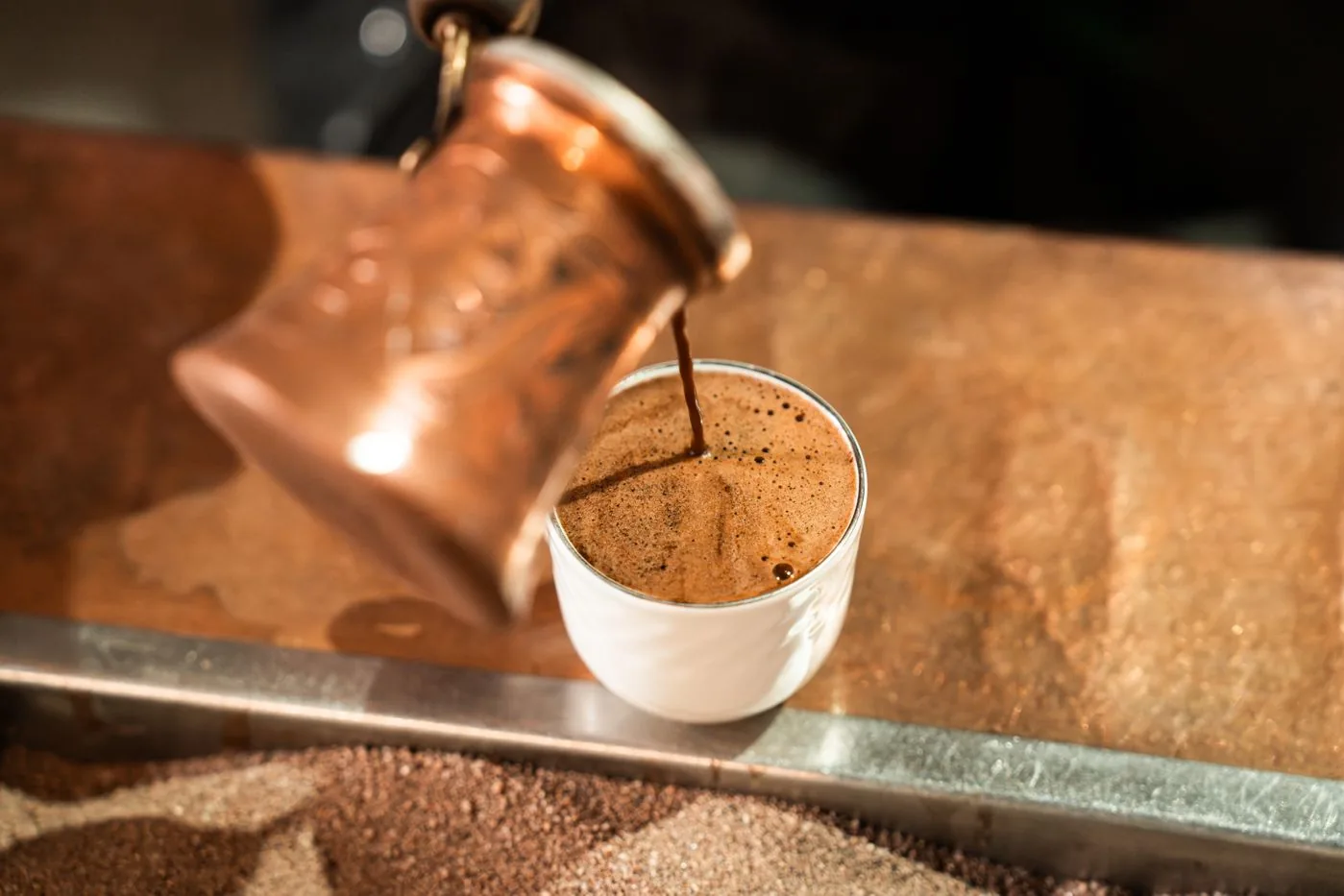 Arabic coffee being poured from a dallah into small cups